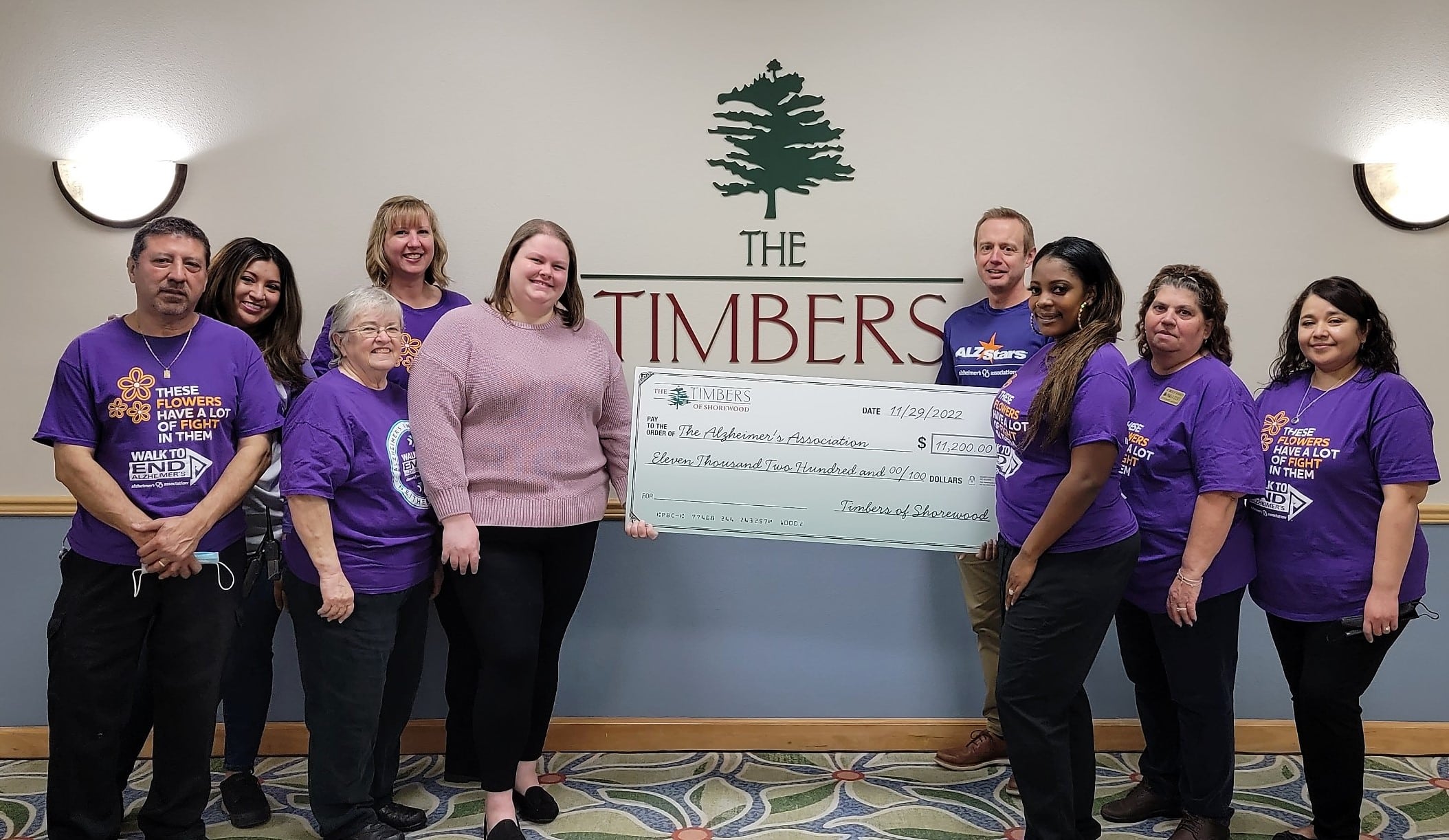 Timbers staff holding check for Alz Donation
