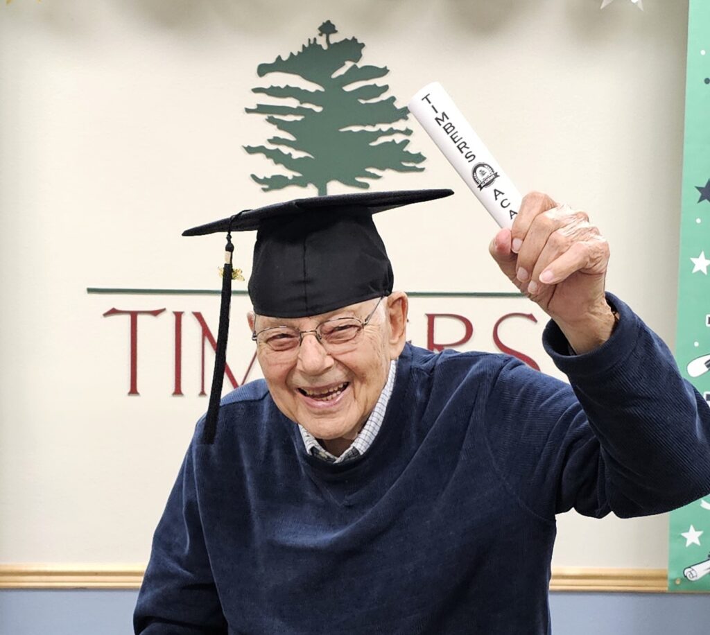 Senior citizen holds graduation certificate from Timbers Academy for Seniors.